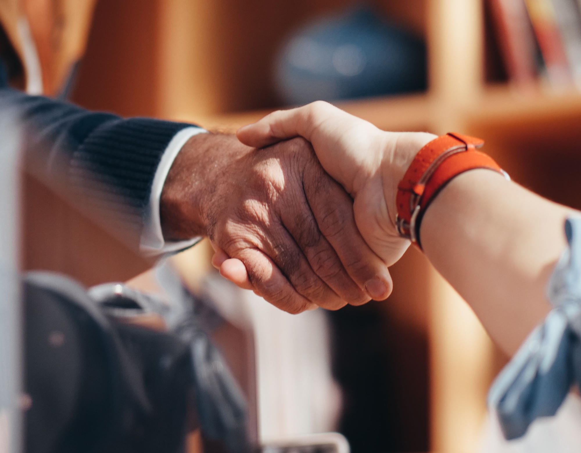 Two people shaking hands across a desk.