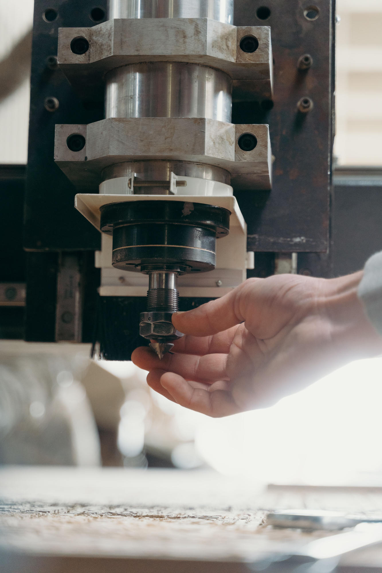 A hand steadying the cutting head of a milling machine.