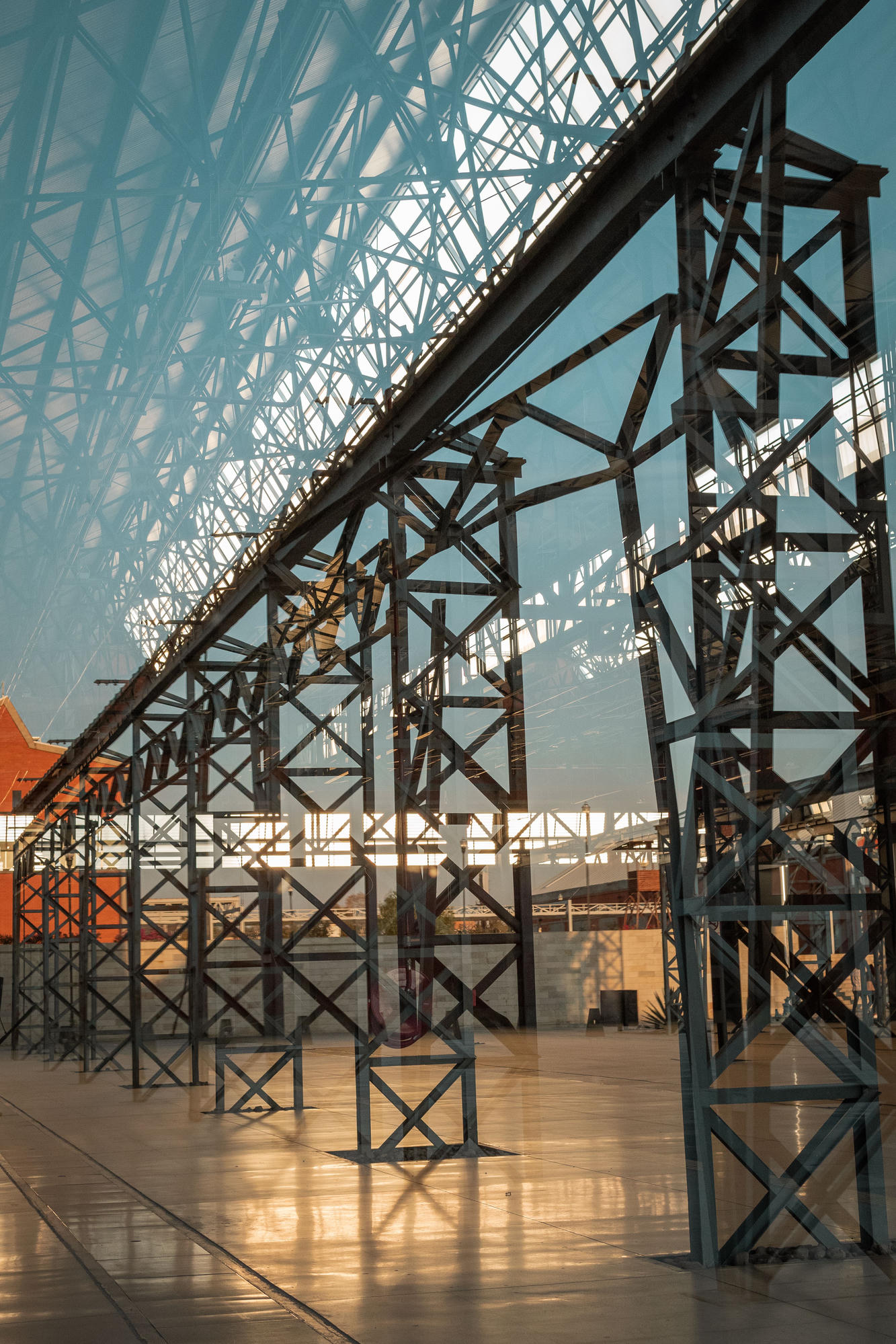 Steel conveyor gantry and lattice towers backlit at sunset