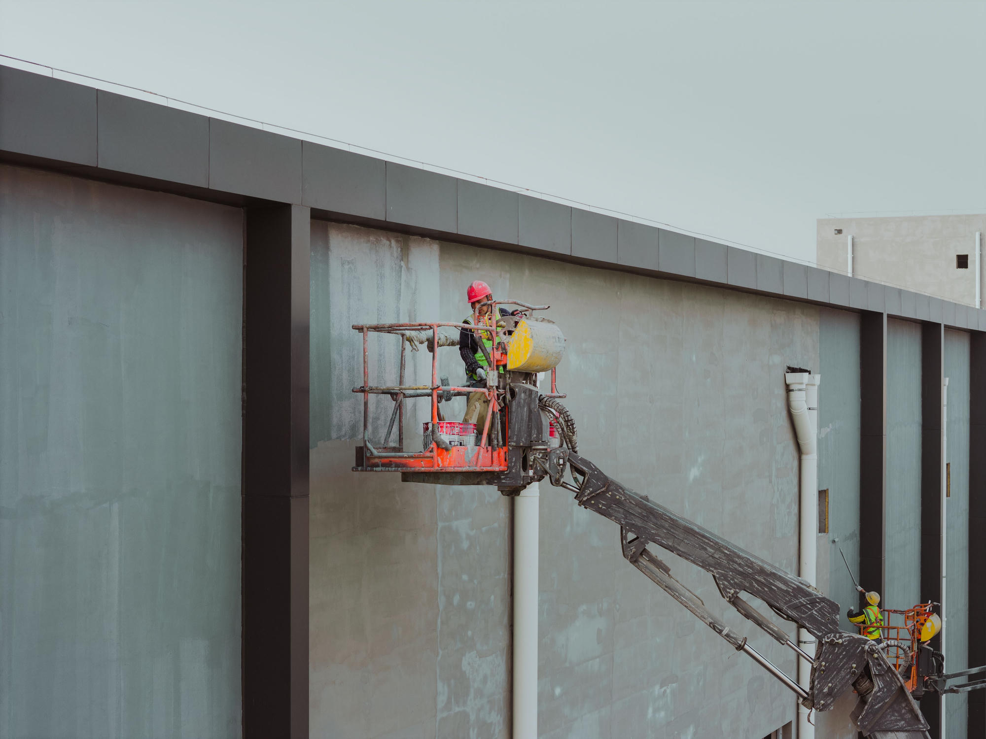 Worker on a boom lift finishing a concrete facade
