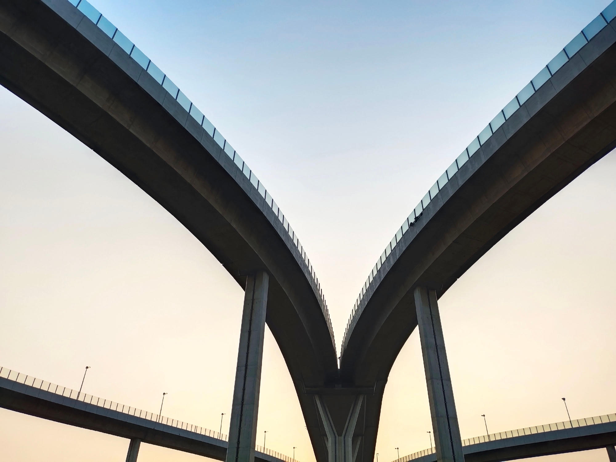 Two elevated roadways splitting apart against a dusk sky
