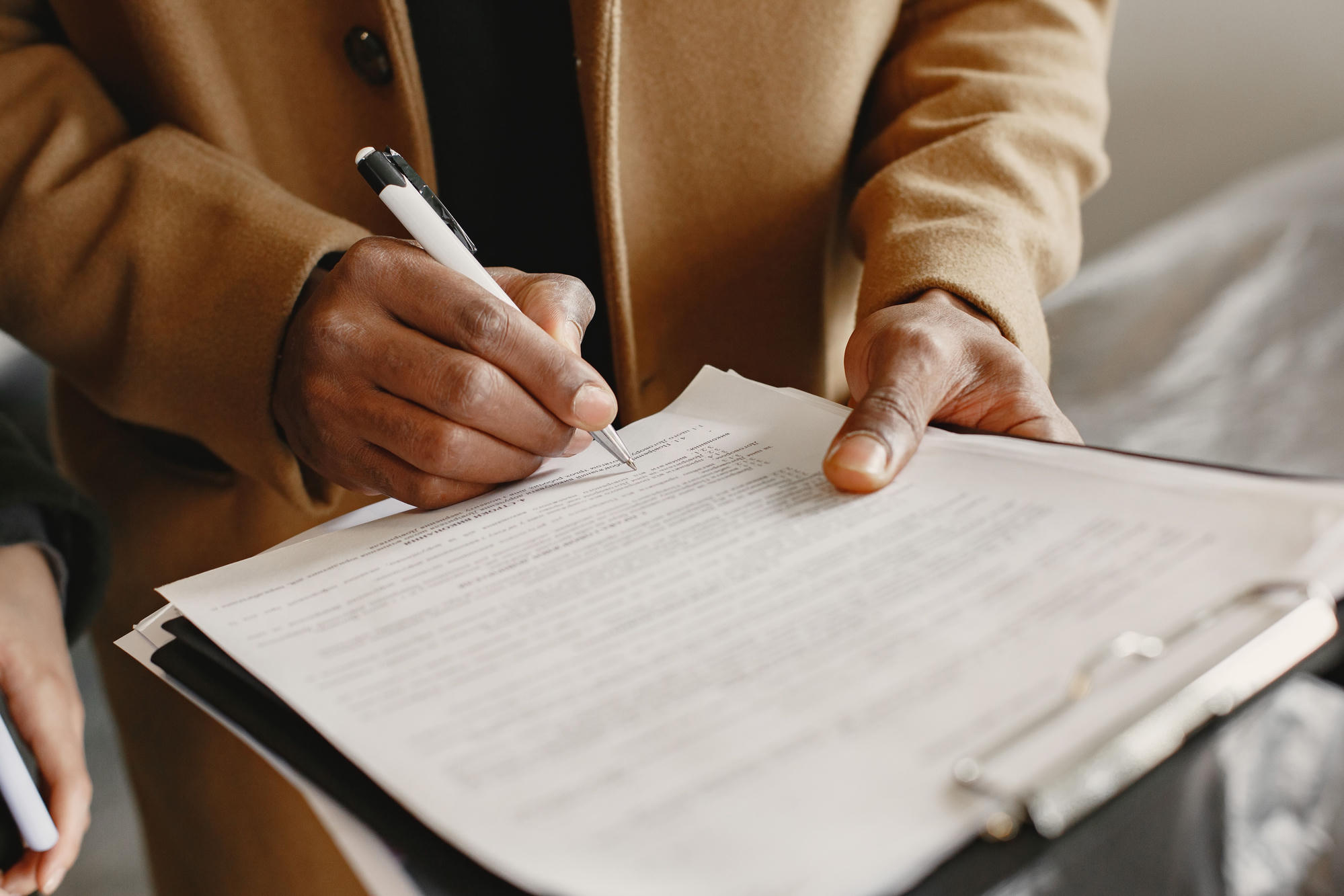 Hands marking up a printed contract on a clipboard