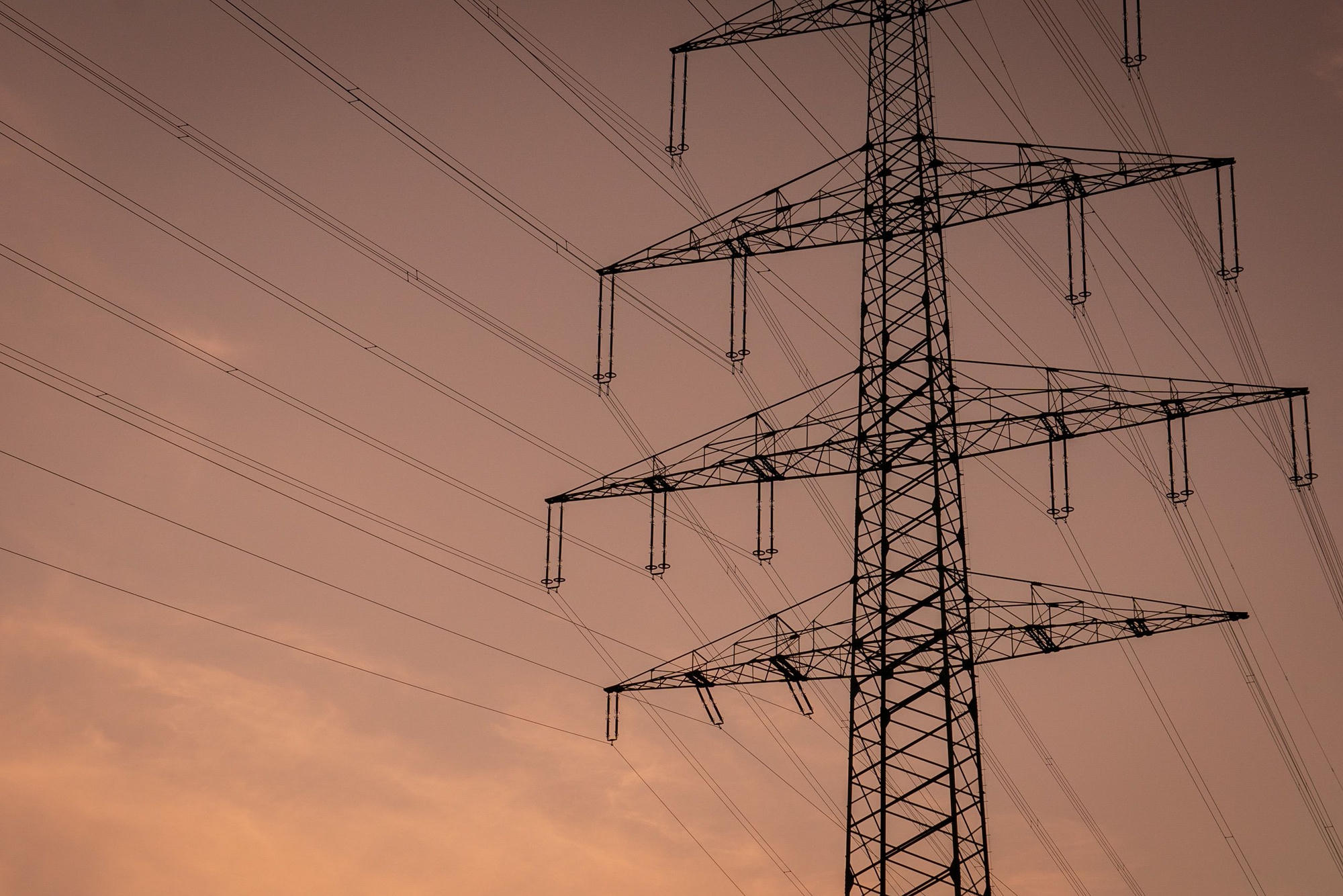 Transmission tower and power lines silhouetted at dusk